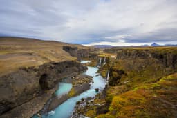 Scenic landscape view of incredible Sigoldugljufur canyon in highlands with turquoise river, Iceland. Volcanic landscape on background. Popular tourist attraction. Beautiful landscape of Sigoldugljufur canyon with many small waterfalls and the blue river in Highlands of Iceland