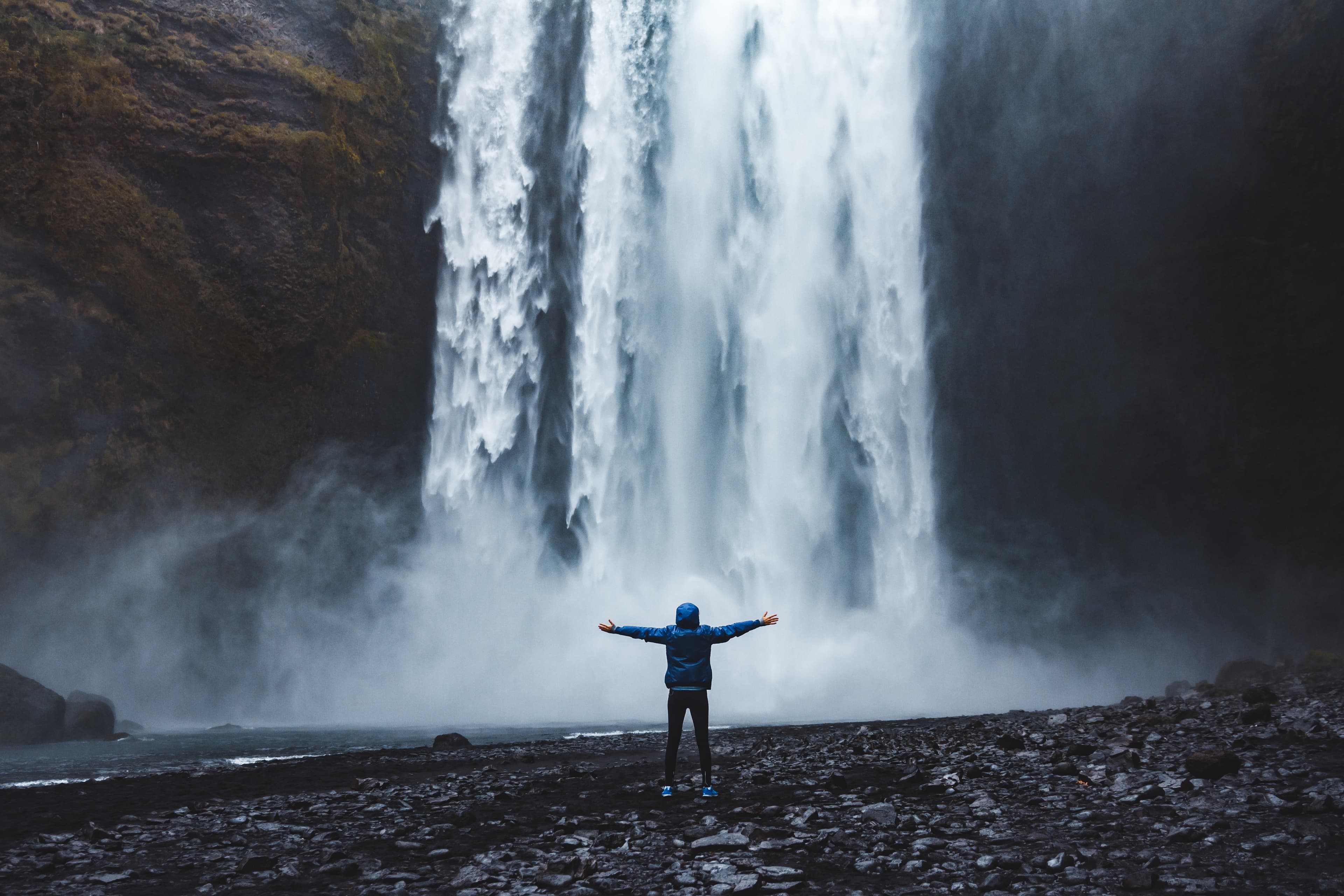 A person admirnig the beauty of Skogafoss waterfall located in Iceland tourist-in-front-of-skogafoss-waterfall
